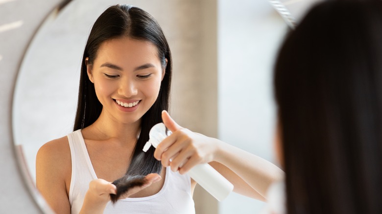 Woman spraying hair with product