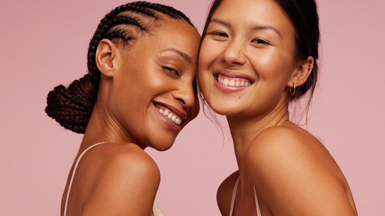 two smiling women against pink background