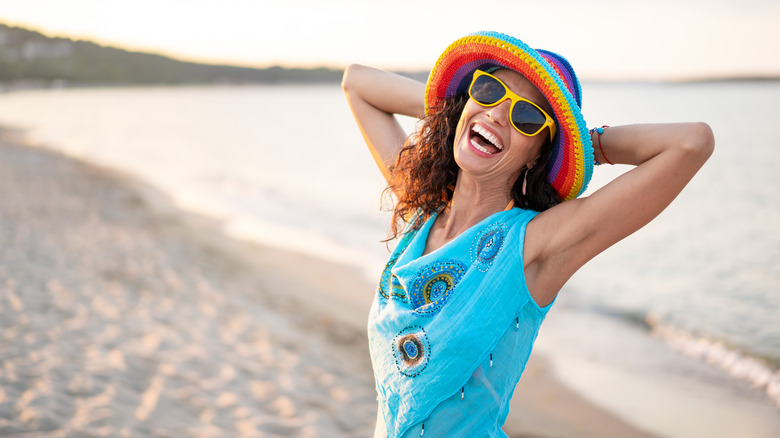 Woman on beach wearing hat and sunglasses