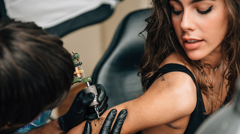 Woman getting tattoo back of arm