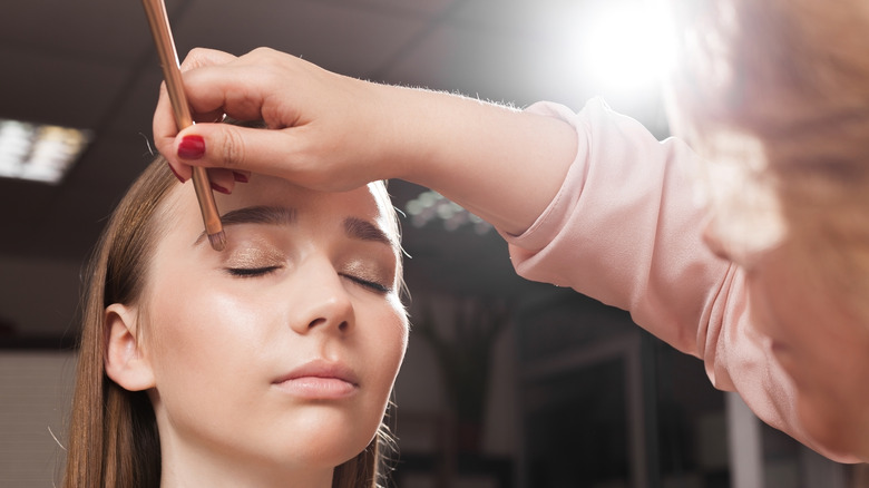 makeup artist applying eyeshadow on model