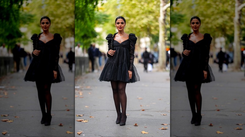 A person posing in a black puffy dress and tights.