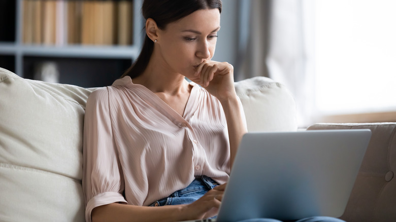 woman looking thoughtfully at laptop