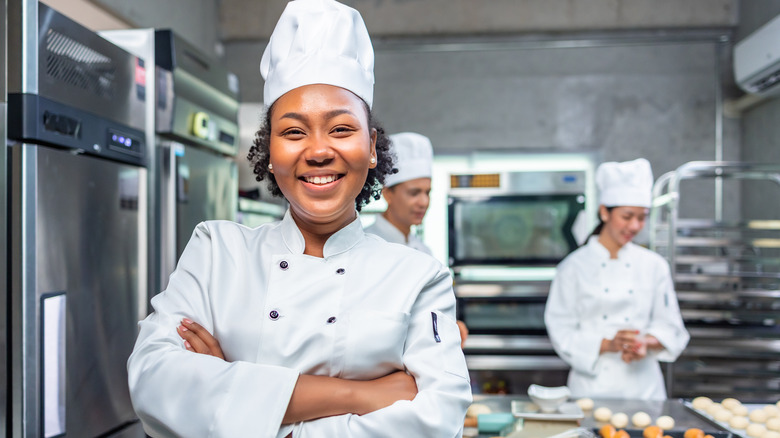 smiling female chef in busy kitchen