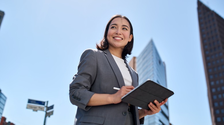 smiling woman holding iPad outside