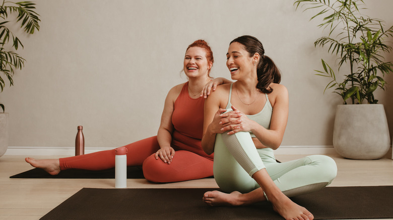 women sitting on yoga mats laughing