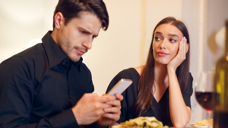 Man ignoring woman at dinner table