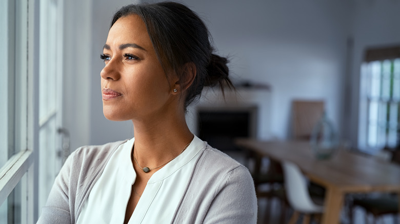 Woman looks out window while deep in thought 