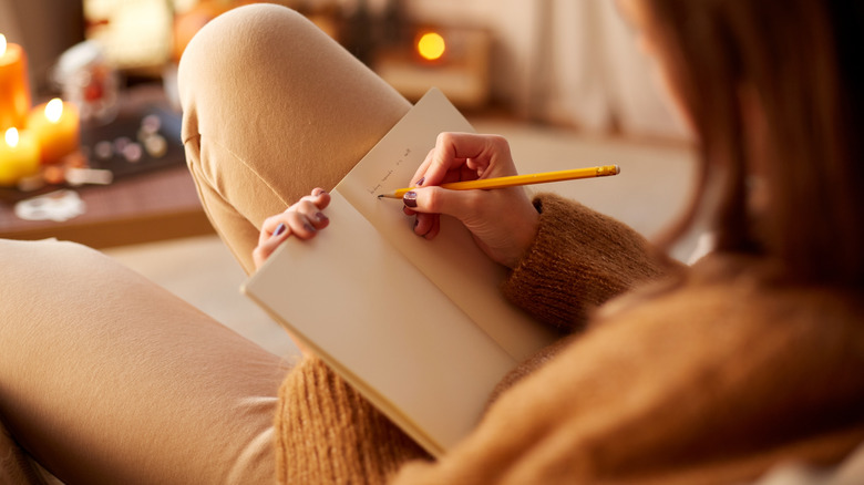 Woman writes in journal on sofa