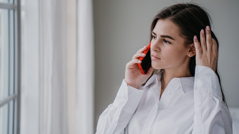 Woman talks on phone with facial expression of resolve 