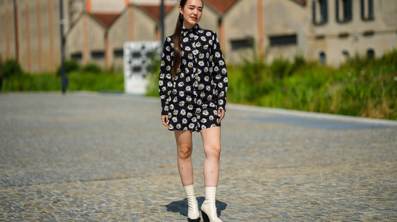 Woman wearing floral romper with ankle boots.