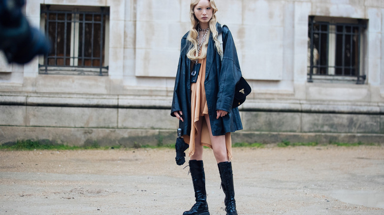 Woman wearing oversize clothing and boots.