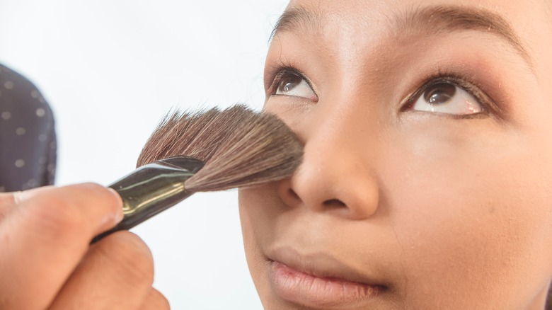 woman using a fan brush under the eyes