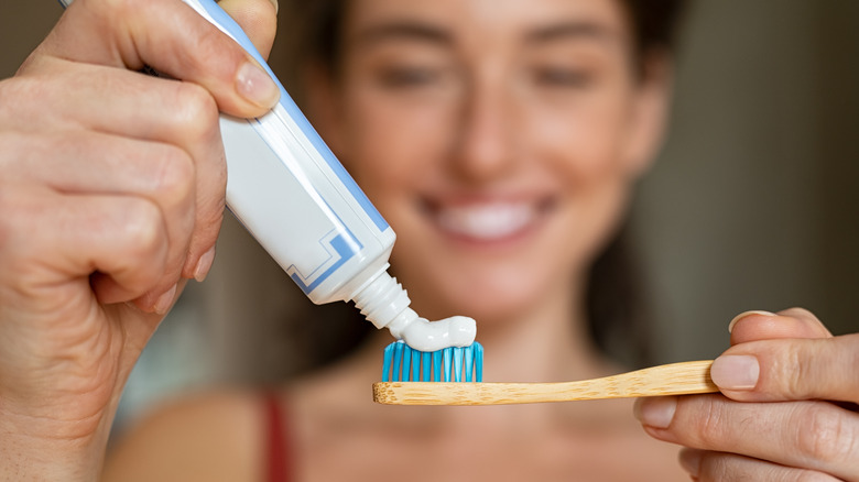 woman applying toothpaste to toothbrush