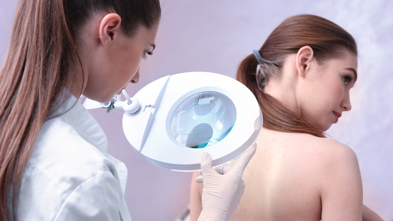 doctor examining patient's back using magnifier