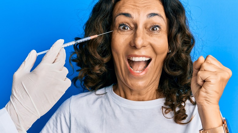gloved doctor's hand with syringe and smiling woman