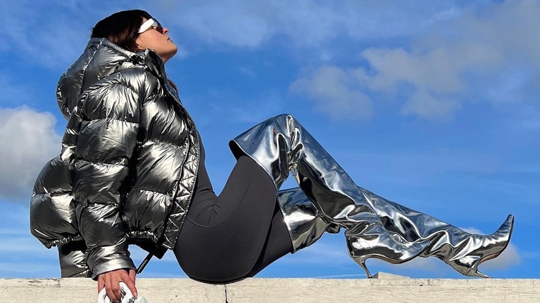 woman sitting on ledge wearing tall metallic silver boots