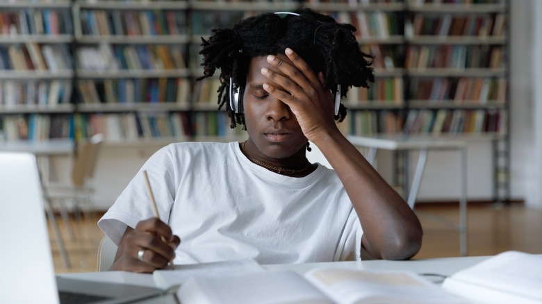 Man sitting at desk with hand on head