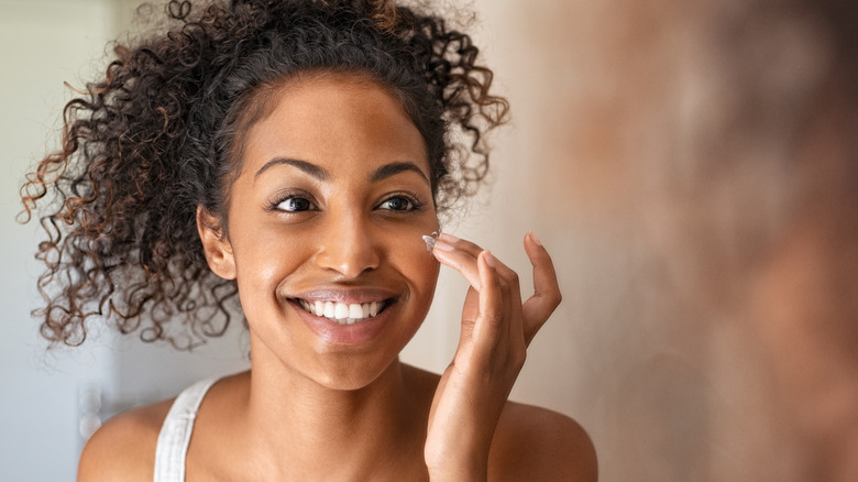 Smiling woman applying moisturizer