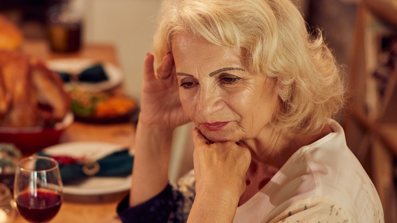 Older model with sad expression at holiday table