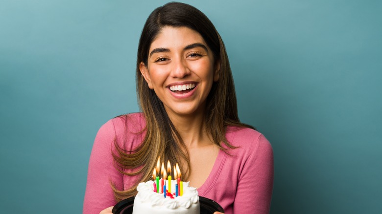 Model holding a small cake with candles