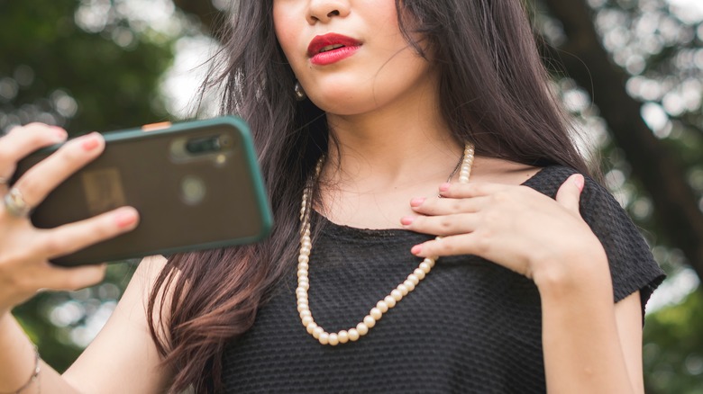 Woman wearing pearls taking selfie