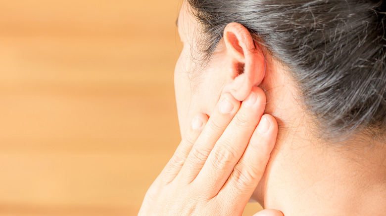 woman touching jaw behind ear