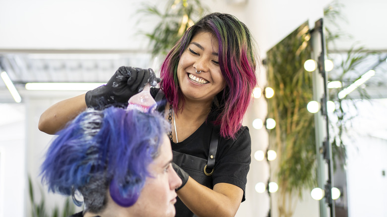 Hairstylist coloring client's hair blue