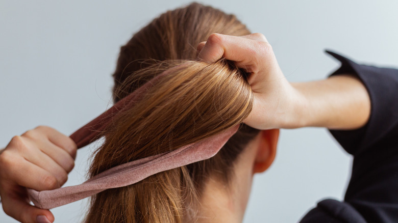 woman pulls hair into ponytail