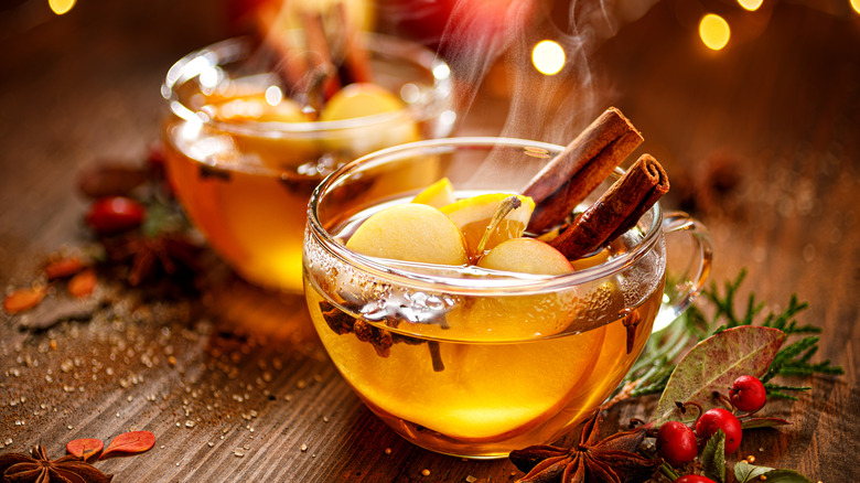 Glass cups of hot apple cider served with cinnamon sticks