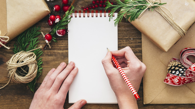 Person writing a list amidst holiday decor 