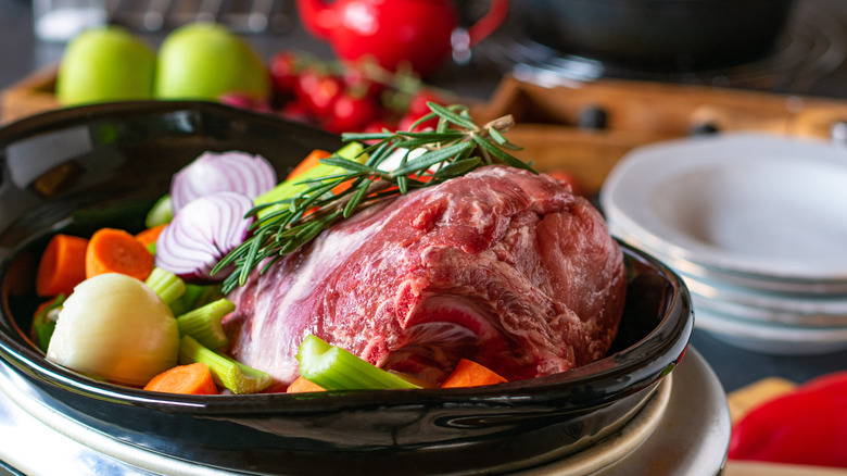 Fresh lamb, rosemary, and chopped vegetables in slow cooker