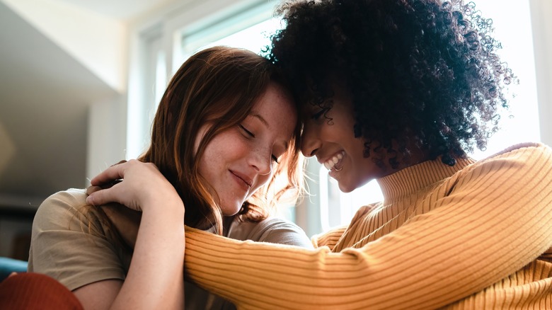 women with heads leaning together