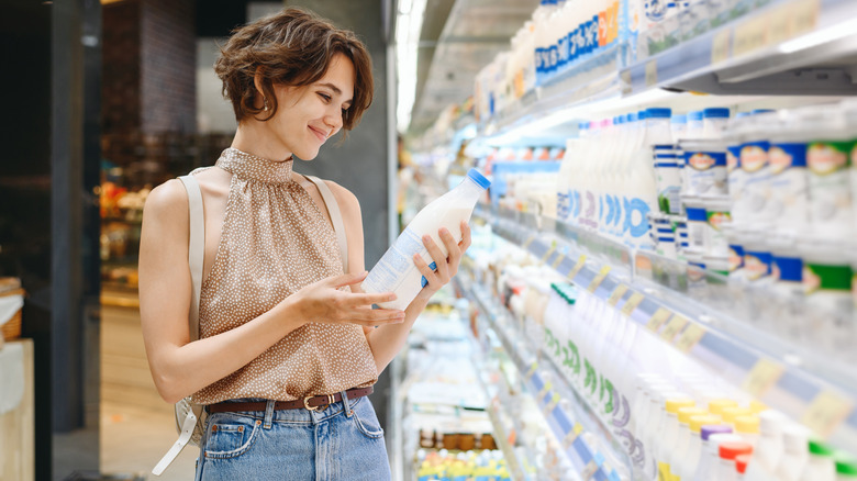 Woman browsing kefir yogurt in dairy aisle at store