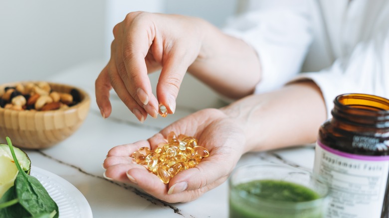 Woman grasping fish oil capsules from hand