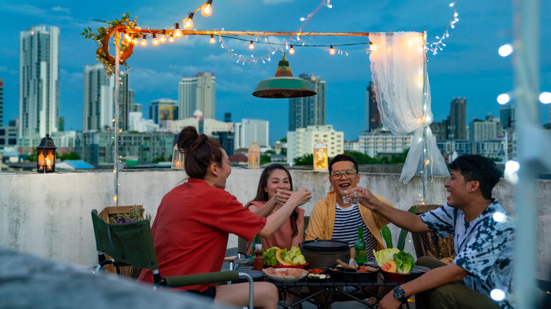 Friends sharing a toast at rooftop gathering overlooking city