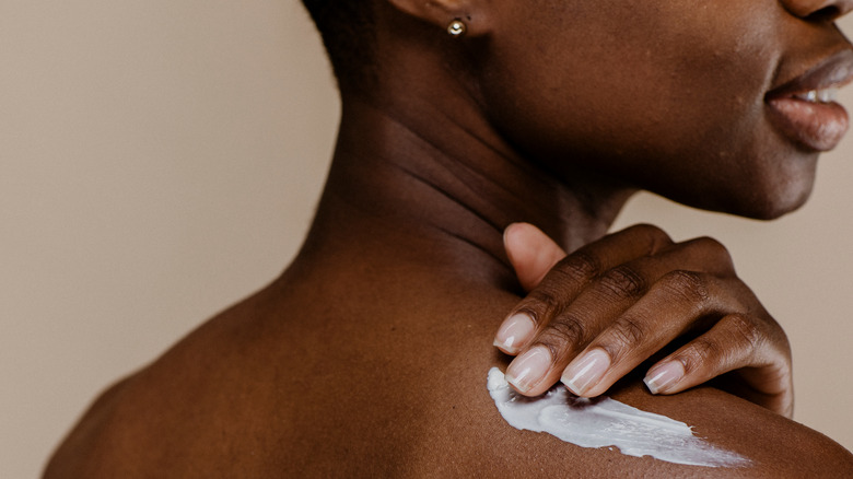 Woman applying lotion in shower