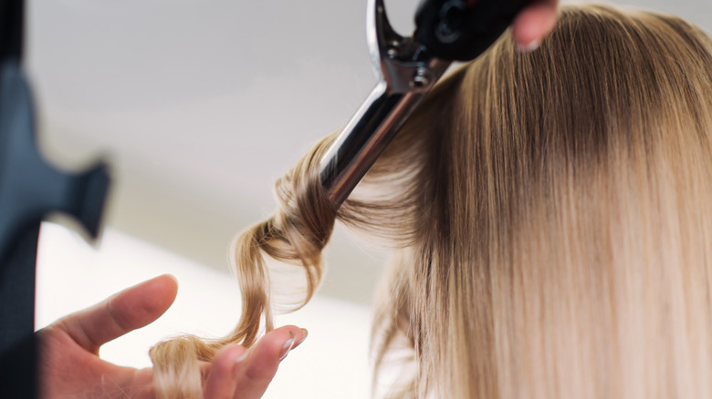 hairstylist curling hair around curling iron