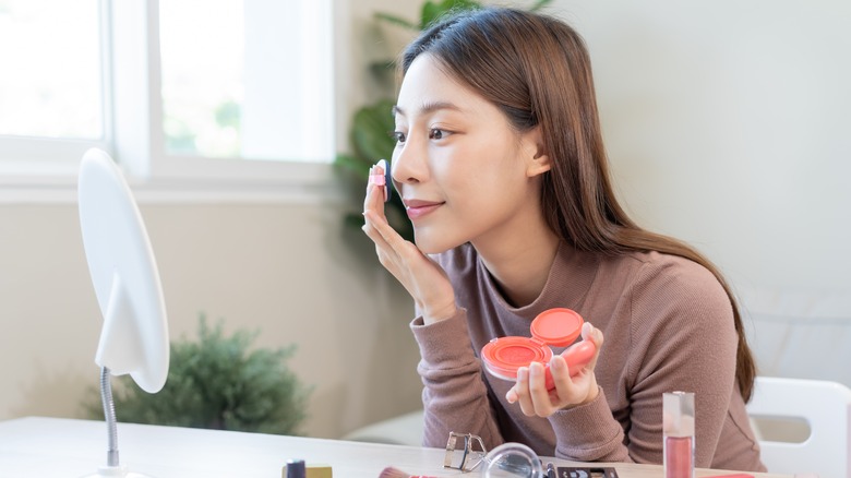 woman applying powder blush 