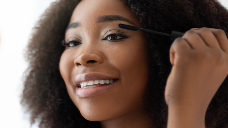 person putting on mascara