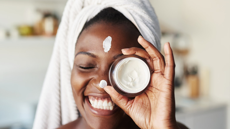 smiling woman holding up cream jar