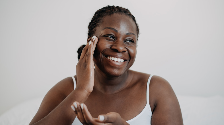 woman applying cream to face