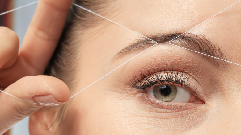 Woman threading eyebrows