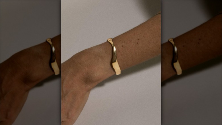 Individual's wrist with gold cuff bracelet 