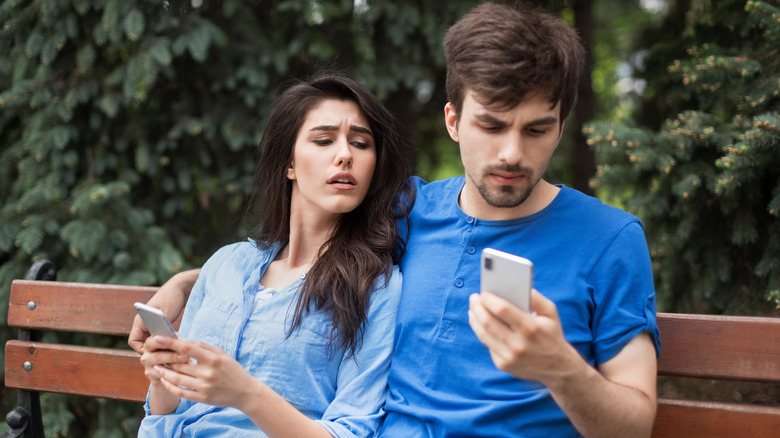 Couple on bench looking at phone