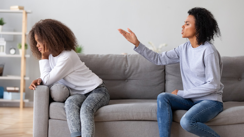 Mother scolding daughter on sofa