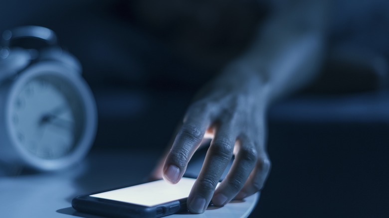 female in bed checking phone