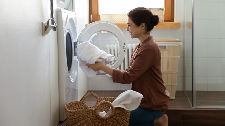 person putting towel in washing machine