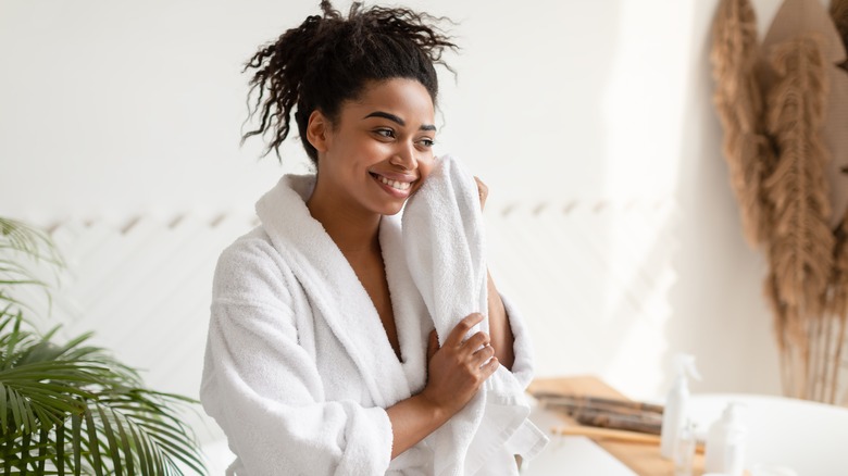 Woman in robe drying face with towel