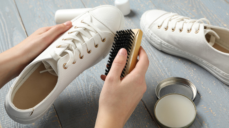 woman cleaning white shoes with a brush